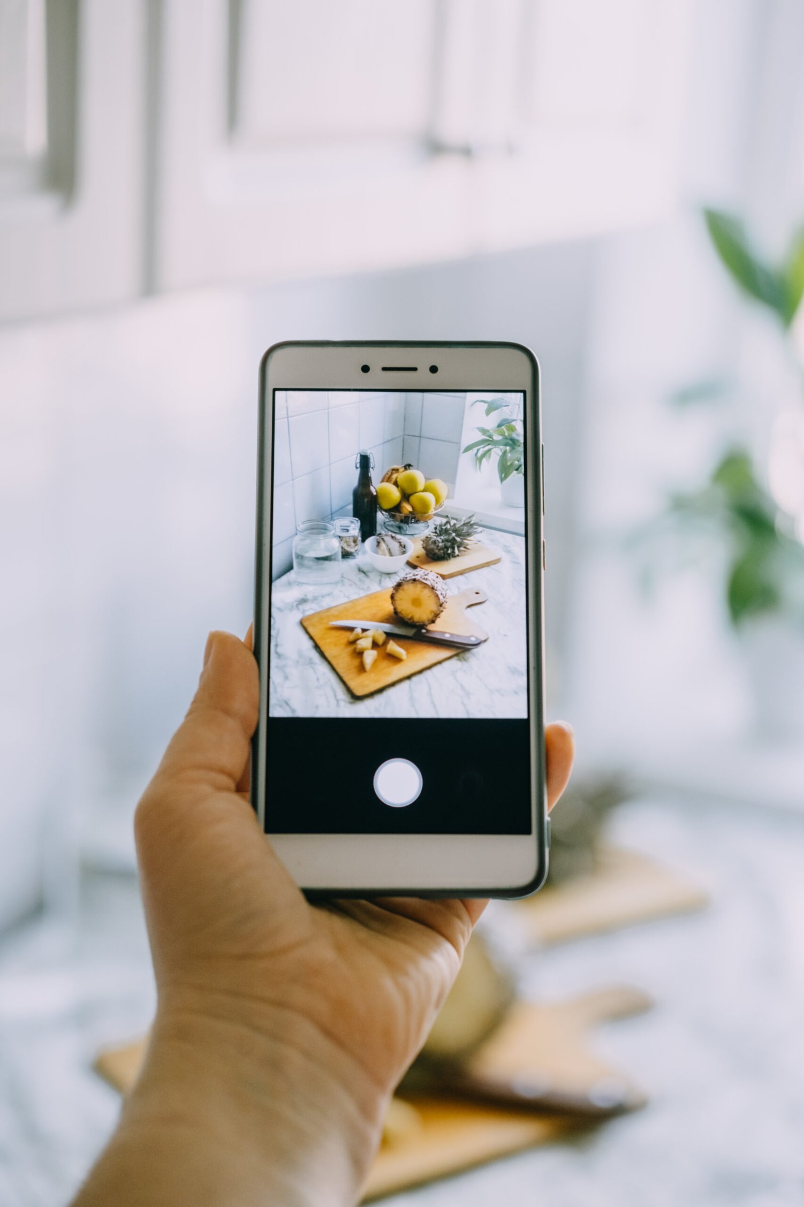 Food blogger takes photo on smartphone for social networks. Female hand holding cell phone with photo of cooking process of homemade Fermented probiotic superfood pineapple beverage